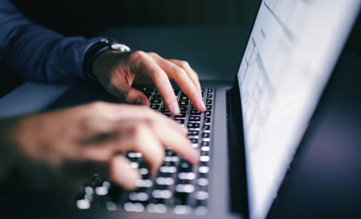 Hands typing on laptop keyboard.